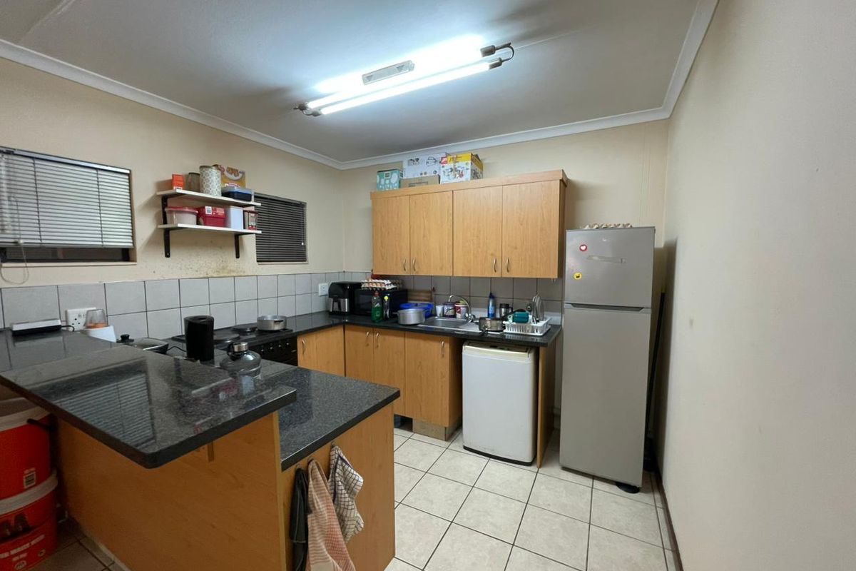 Functional kitchen featuring laminate cabinetry, granite countertops, tiled backsplash, and ceramic flooring, offering a practical layout for daily meal preparation.