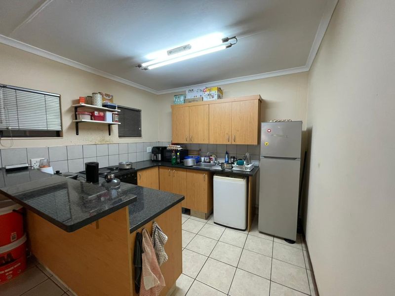 Functional kitchen featuring laminate cabinetry, granite countertops, tiled backsplash, and ceramic flooring, offering a practical layout for daily meal preparation.