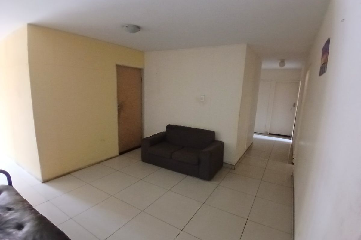 A simple living area featuring tiled flooring and neutral wall finishes, providing a blank canvas for potential interior updates.