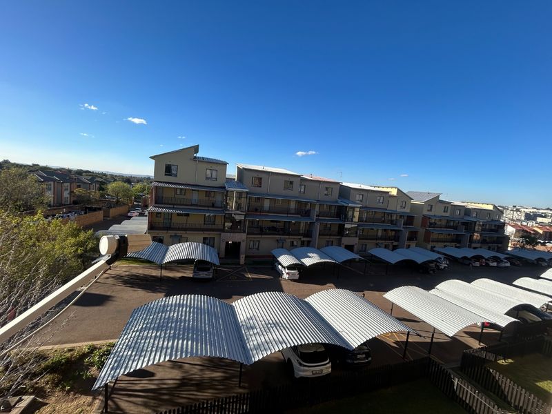 Elevated view of the apartment complex exterior, featuring multiple residential blocks with balconies and extensive covered parking bays.