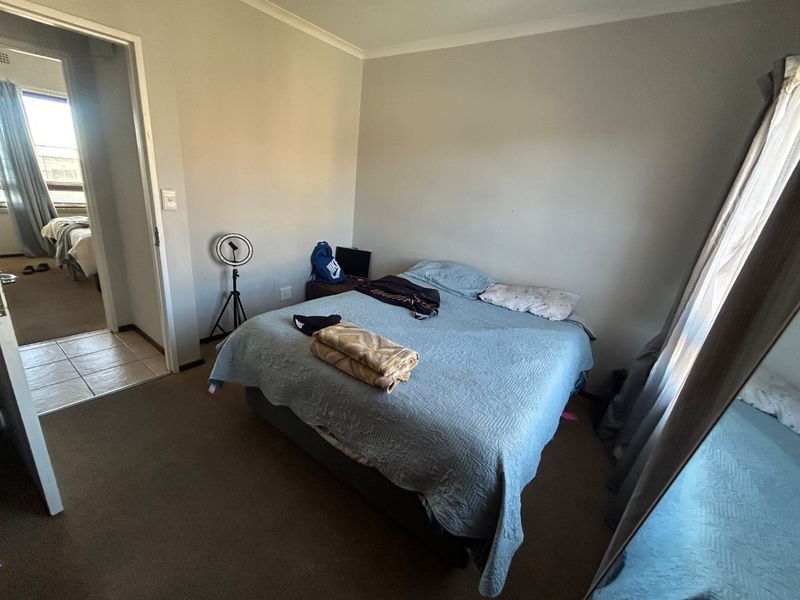 A standard bedroom featuring carpeted flooring and neutral wall finishes, with an adjacent view into a secondary room.