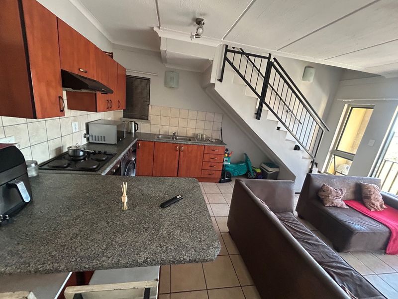 Open-plan kitchen and living area featuring granite countertops, built-in cabinetry, and a staircase leading to the upper level.