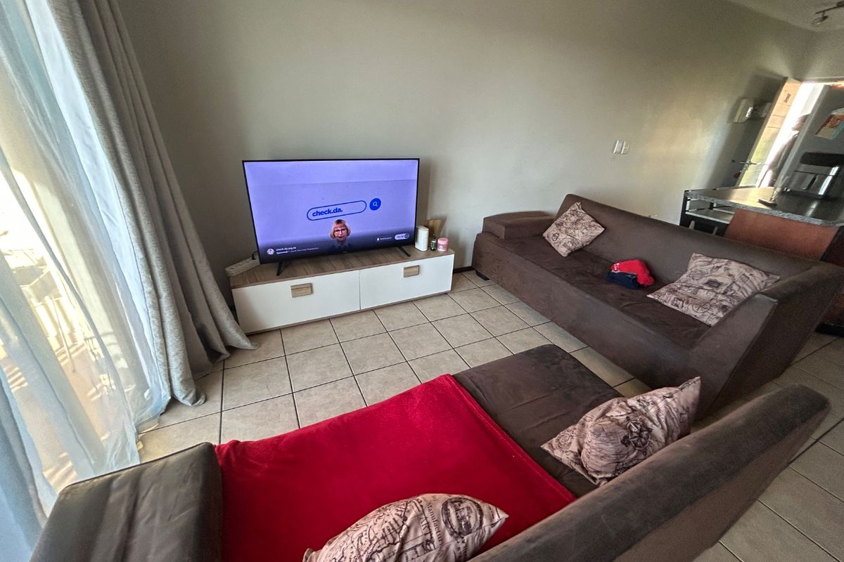 A living room area featuring tiled flooring and a sliding glass door providing natural light access.