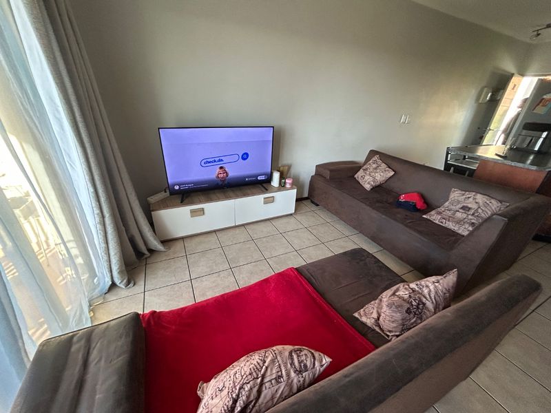 A living room area featuring tiled flooring and a sliding glass door providing natural light access.