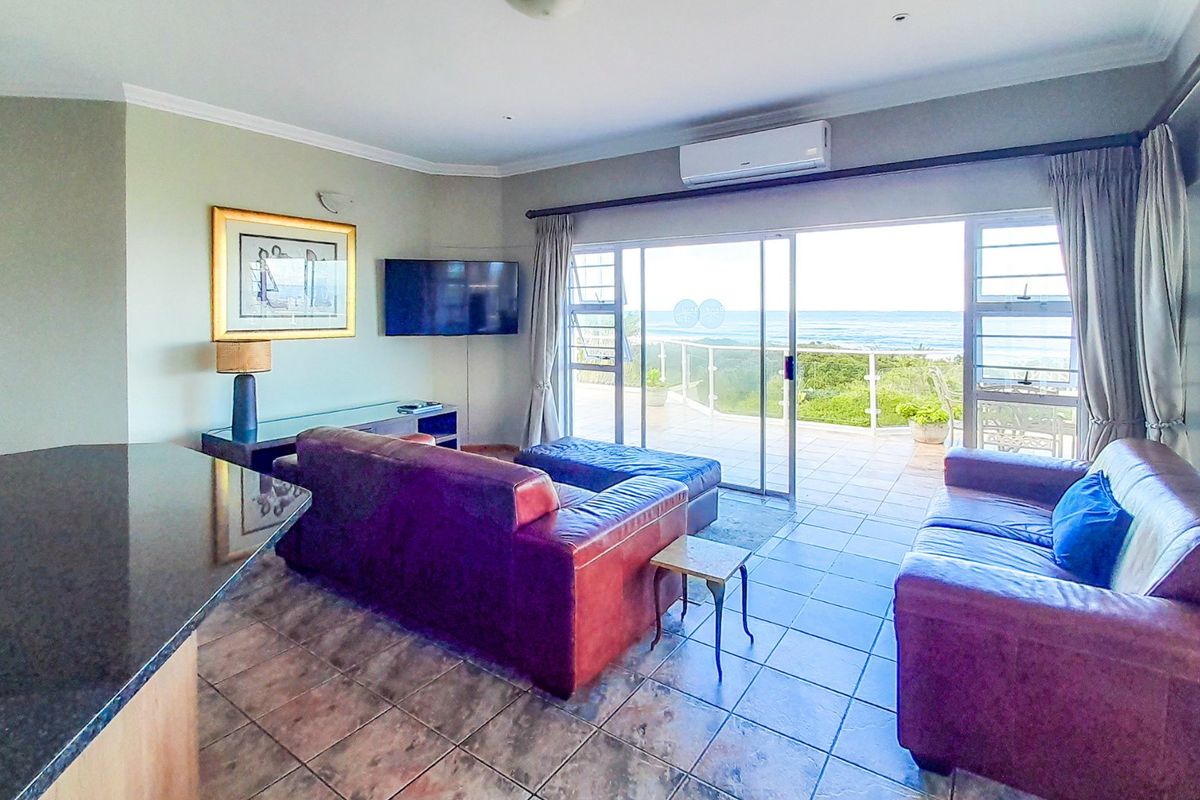 Spacious living room featuring tiled floors and large sliding glass doors that open onto a balcony with scenic ocean views.