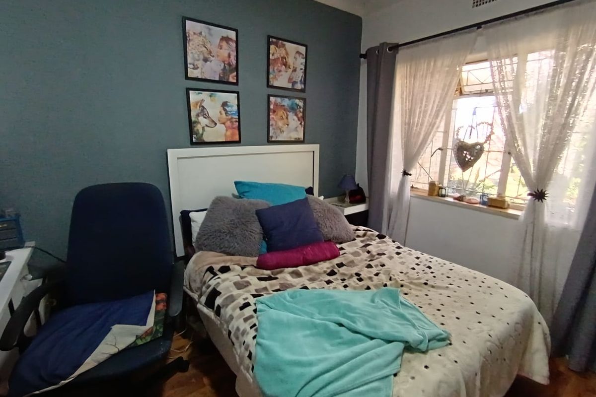A bedroom featuring parquet flooring, a window with security bars, and a ceiling air vent.