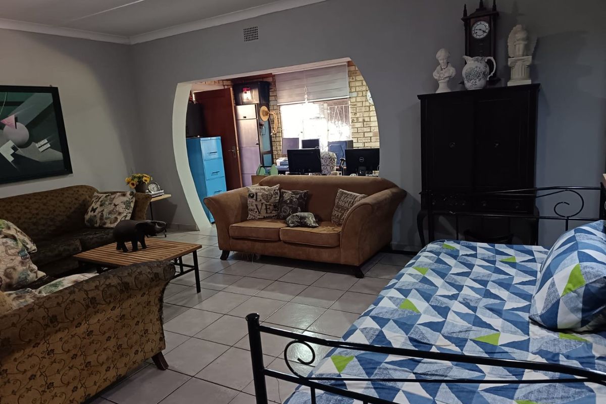 A spacious living area featuring tiled flooring and a distinctive arched opening leading to an adjacent room, providing a functional and open layout.