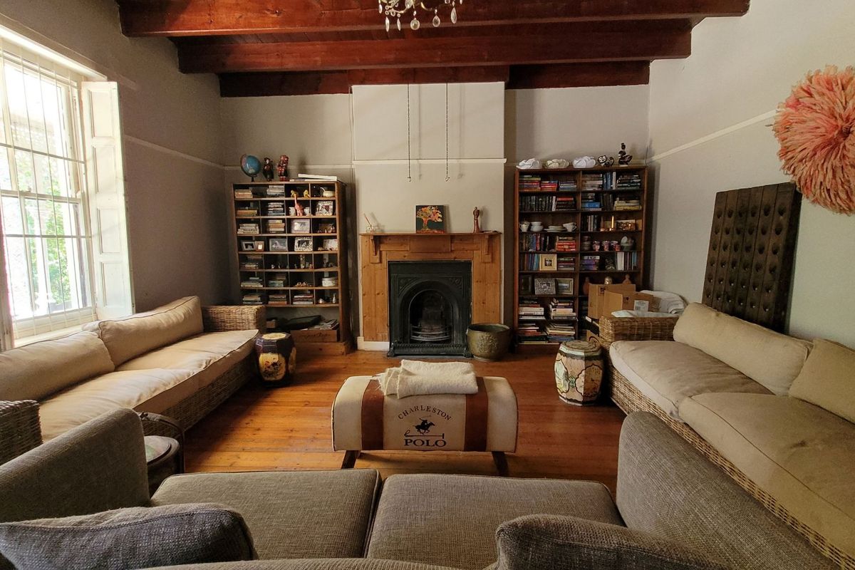 Spacious living room featuring exposed timber ceiling beams, original timber flooring, and a classic cast iron fireplace with a timber mantel.