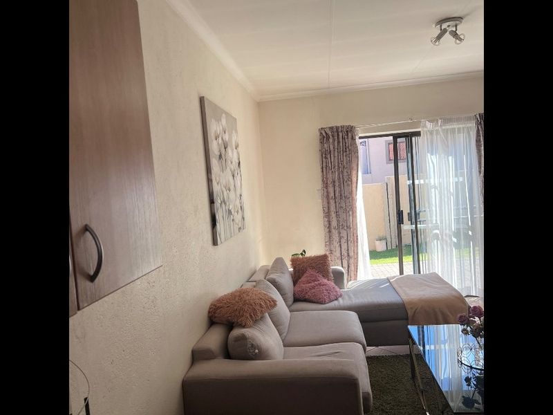 A living room featuring tiled flooring and a sliding glass door providing access to the outdoor area.