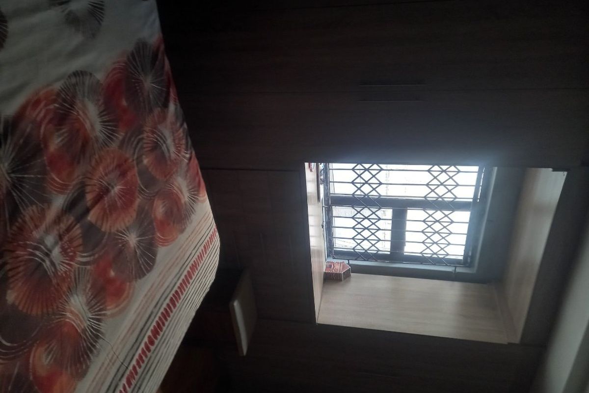 A bedroom featuring built-in cupboards and a window with a security gate.