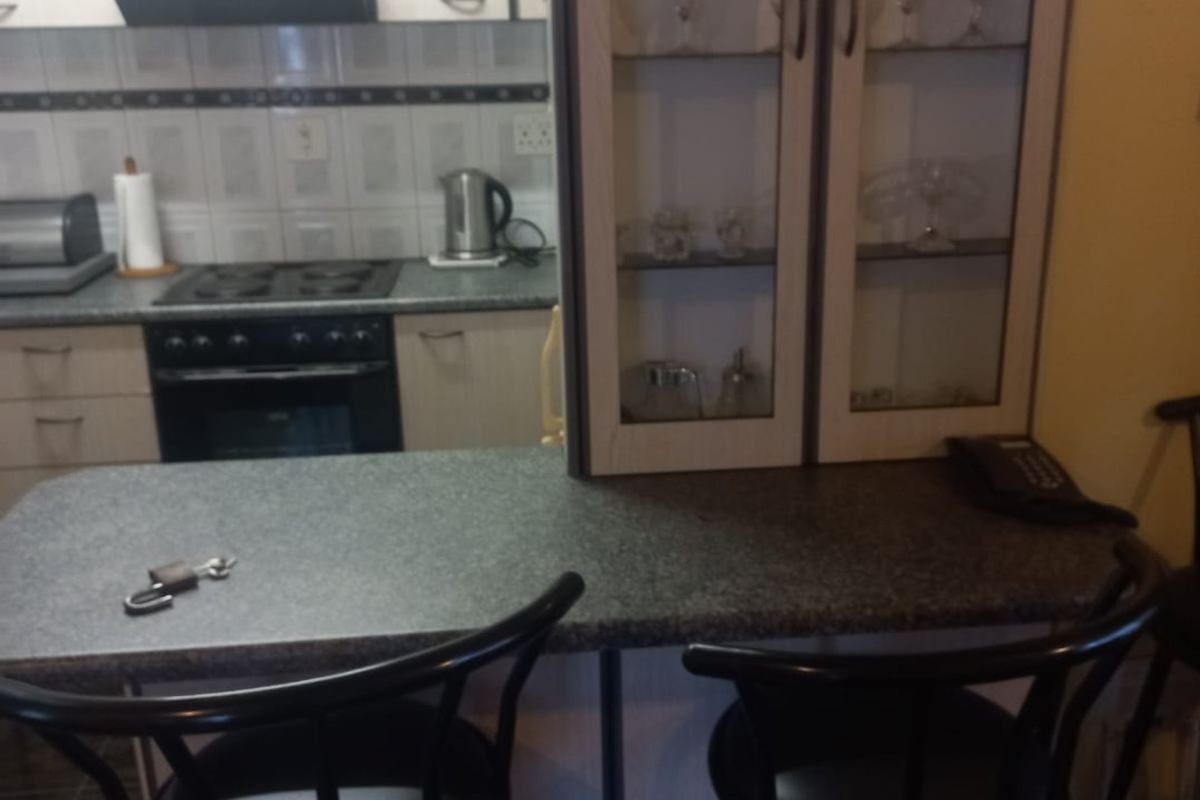 A functional kitchen featuring built-in cabinetry, a breakfast bar with a stone-look countertop, integrated oven and stove, and a glass-front display cabinet.