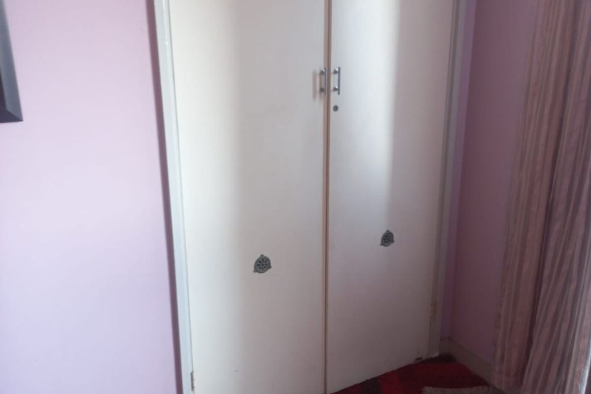 A bedroom featuring a built-in wardrobe with integrated overhead storage cupboards, providing functional storage space.