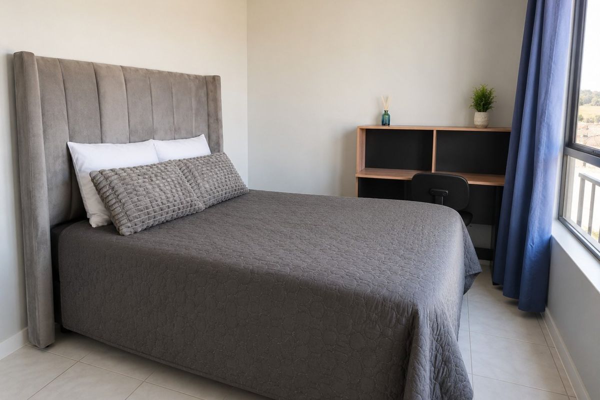 A well-lit bedroom featuring neutral tiled flooring and a large window, providing a clean and comfortable living space.