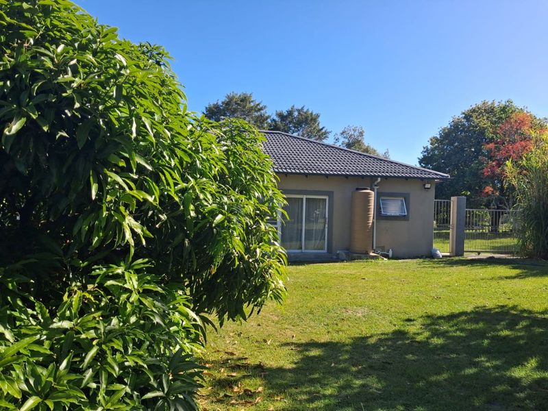 Rear view of the property featuring a tiled roof, sliding glass doors, and a water storage tank set within a private garden area.
