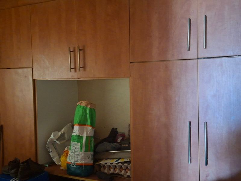 A bedroom featuring extensive built-in timber cabinetry with integrated storage compartments and modern metal handles.