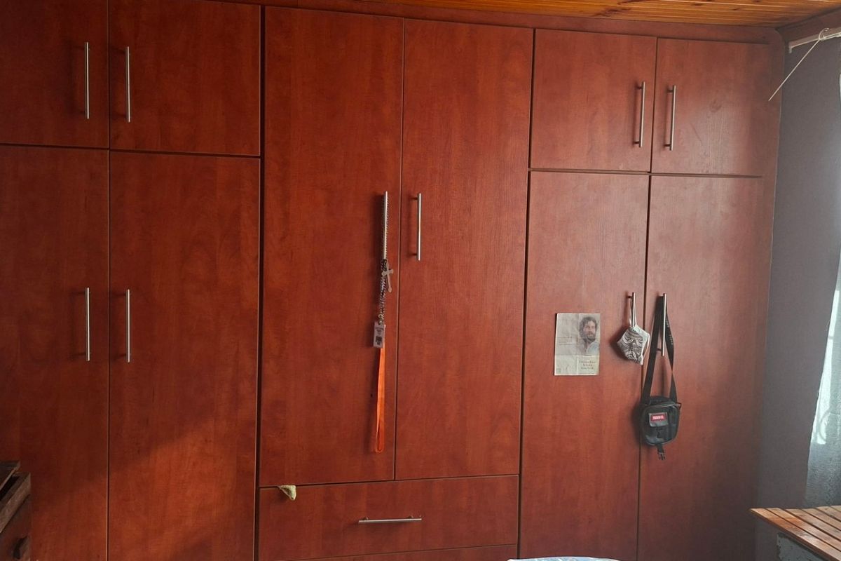 A bedroom featuring extensive floor-to-ceiling built-in wooden cupboards and a timber-clad ceiling.