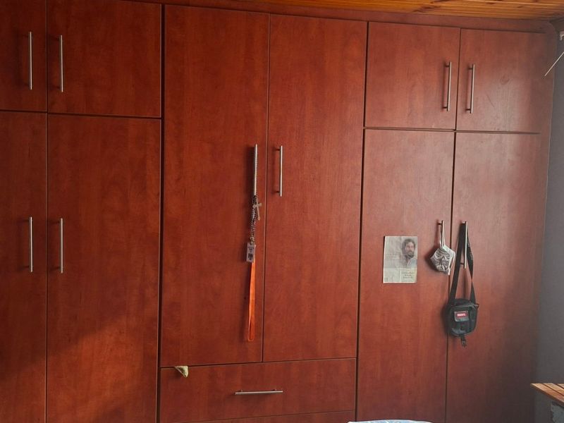 A bedroom featuring extensive floor-to-ceiling built-in wooden cupboards and a timber-clad ceiling.