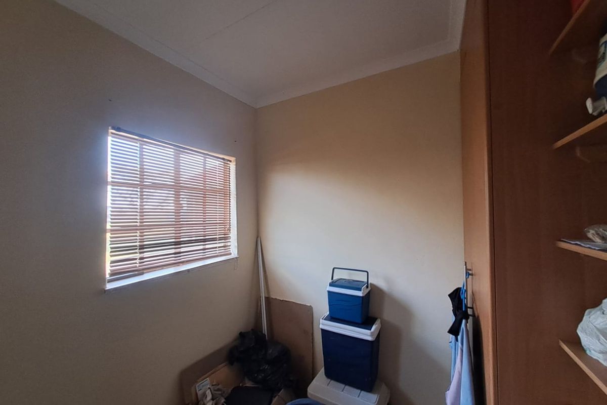 A compact bedroom featuring a built-in wardrobe and a window fitted with venetian blinds, offering a functional space ready for personalization.