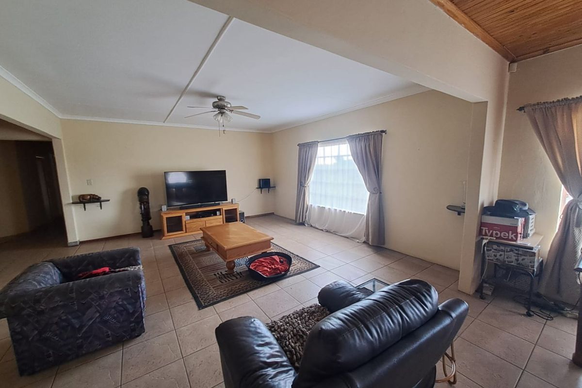 Spacious living room featuring tiled flooring, a timber ceiling, and a ceiling fan, offering a comfortable and functional layout.