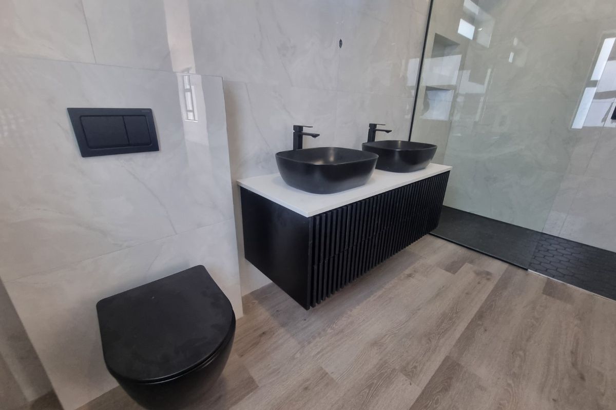 Modern bathroom featuring a floating double vanity with vessel sinks, black matte fixtures, wall-mounted toilet, and a spacious walk-in shower with glass enclosure.
