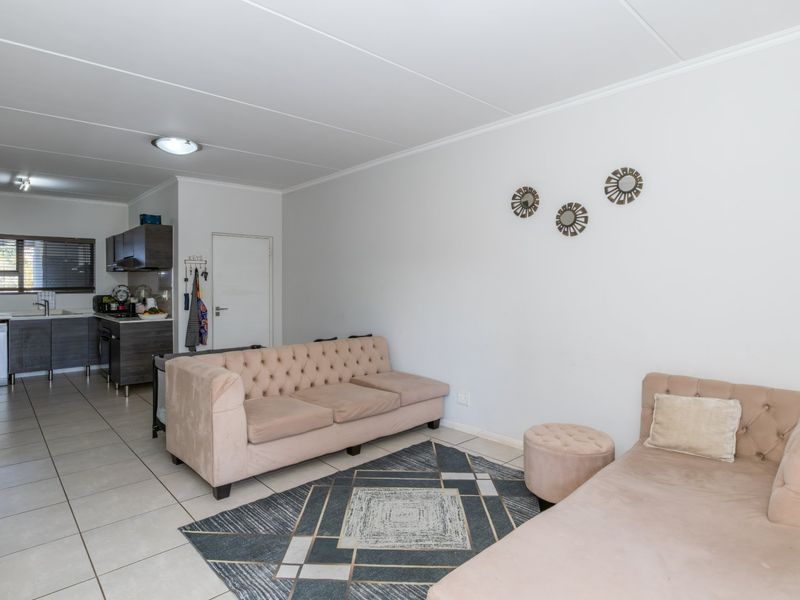 Open-plan living area featuring tiled flooring and a functional kitchen with built-in cabinetry, oven, and hob.