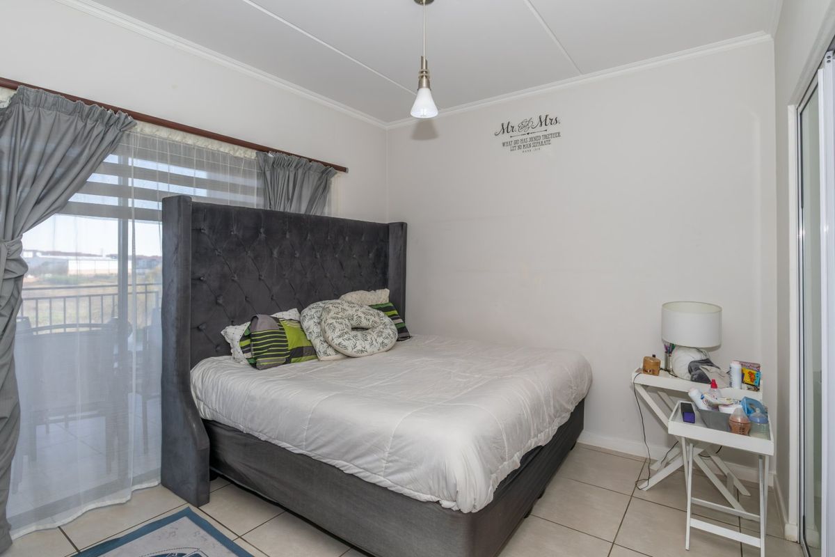 A bedroom featuring tiled flooring and a sliding glass door providing access to an outdoor area, illuminated by a central pendant light.
