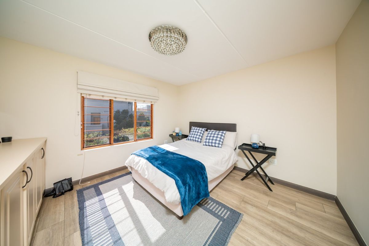 A well-lit bedroom featuring light laminate flooring, built-in cabinetry, and a decorative crystal light fixture.