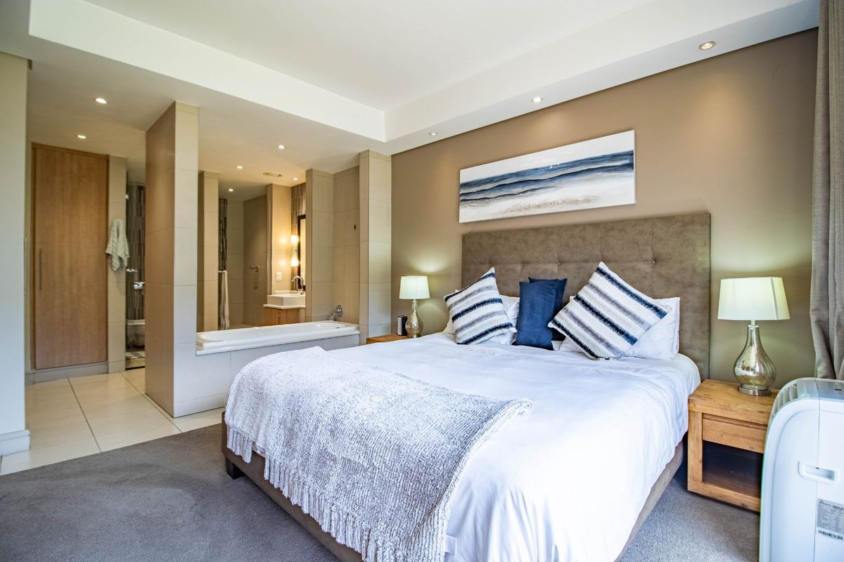 Spacious bedroom featuring an open-plan en-suite bathroom with a built-in bathtub, recessed lighting, and a neutral color palette.
