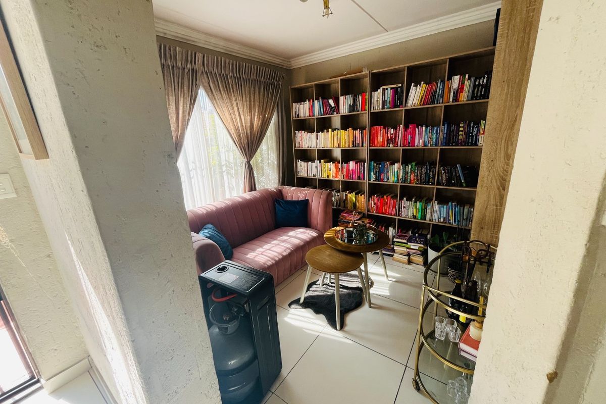 A cozy living area featuring built-in floor-to-ceiling shelving and tiled flooring, offering a functional space for relaxation or a home library.