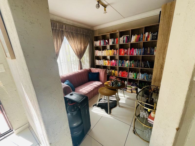 A cozy living area featuring built-in floor-to-ceiling shelving and tiled flooring, offering a functional space for relaxation or a home library.