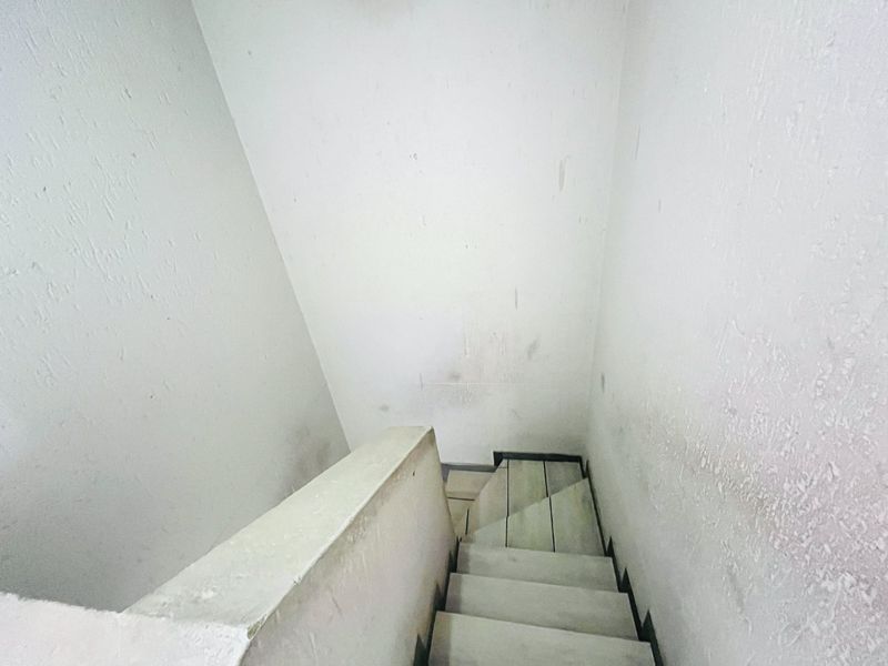 A narrow interior stairwell featuring plain walls and stairs, currently showing significant signs of wear and surface staining requiring maintenance or cosmetic updates.