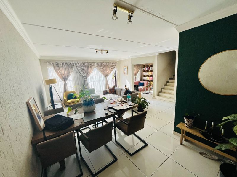 Spacious open-plan living and dining area featuring tiled flooring, a staircase, and modern accent wall, offering a versatile layout for family living.