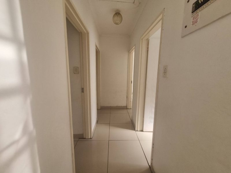 A functional hallway featuring tiled flooring and access to multiple rooms, with a wall-mounted electrical distribution board.