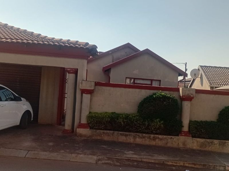 Front elevation of a residential property featuring a tiled roof, integrated garage, and a perimeter boundary wall.