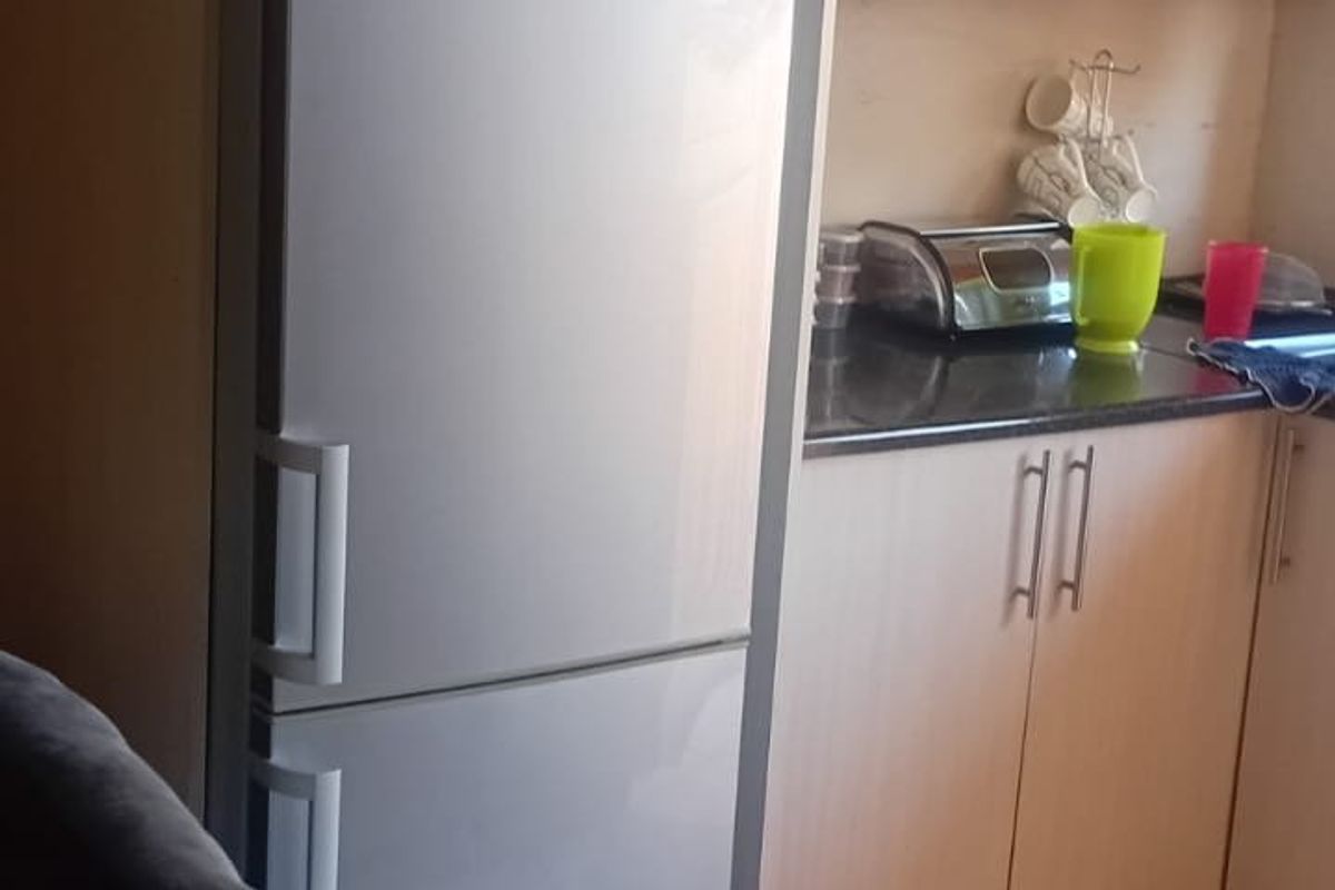A functional kitchen featuring light-toned laminate cabinetry, dark granite countertops, and tiled flooring with a dedicated built-in microwave space.