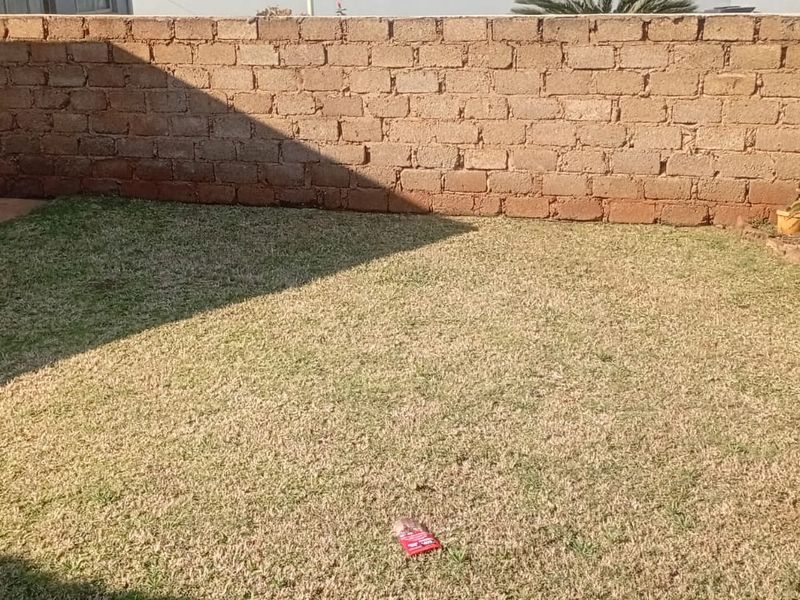 A small private garden area enclosed by exposed brick boundary walls, featuring a grass lawn.