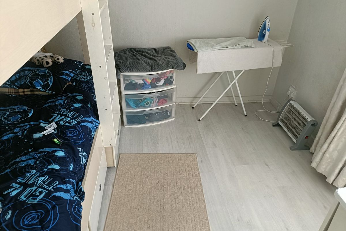 A functional bedroom featuring light-toned laminate flooring and neutral wall finishes, providing a clean and versatile space.