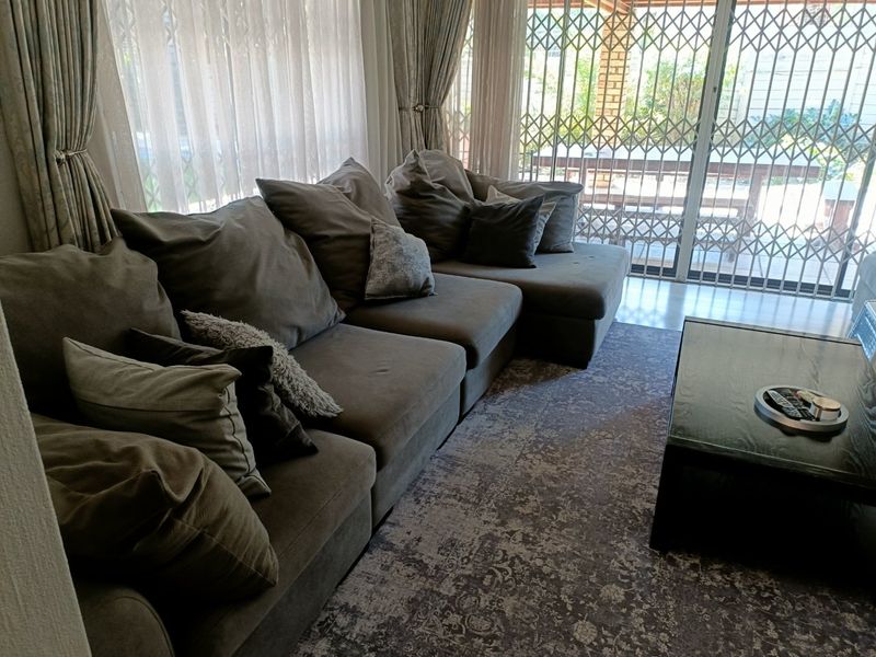 A comfortable living room featuring large sliding glass doors with security gates, providing natural light and access to the outdoor patio area.