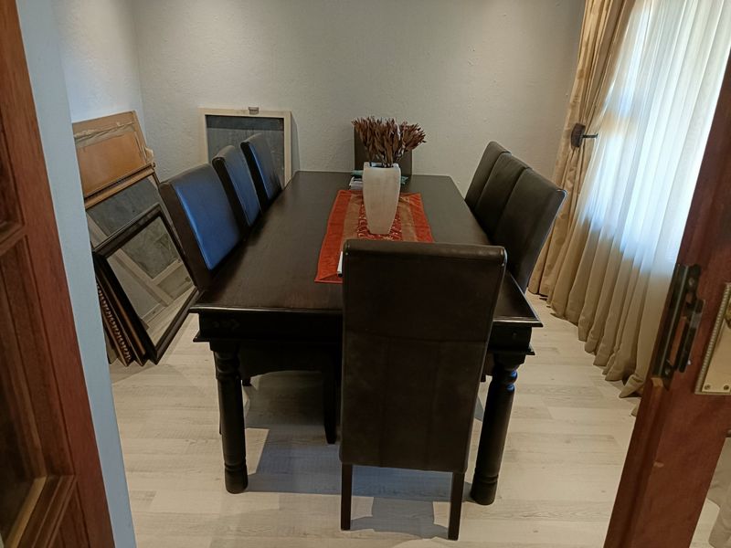 A dining room featuring light-toned laminate flooring and window curtains, providing a functional space for meals.
