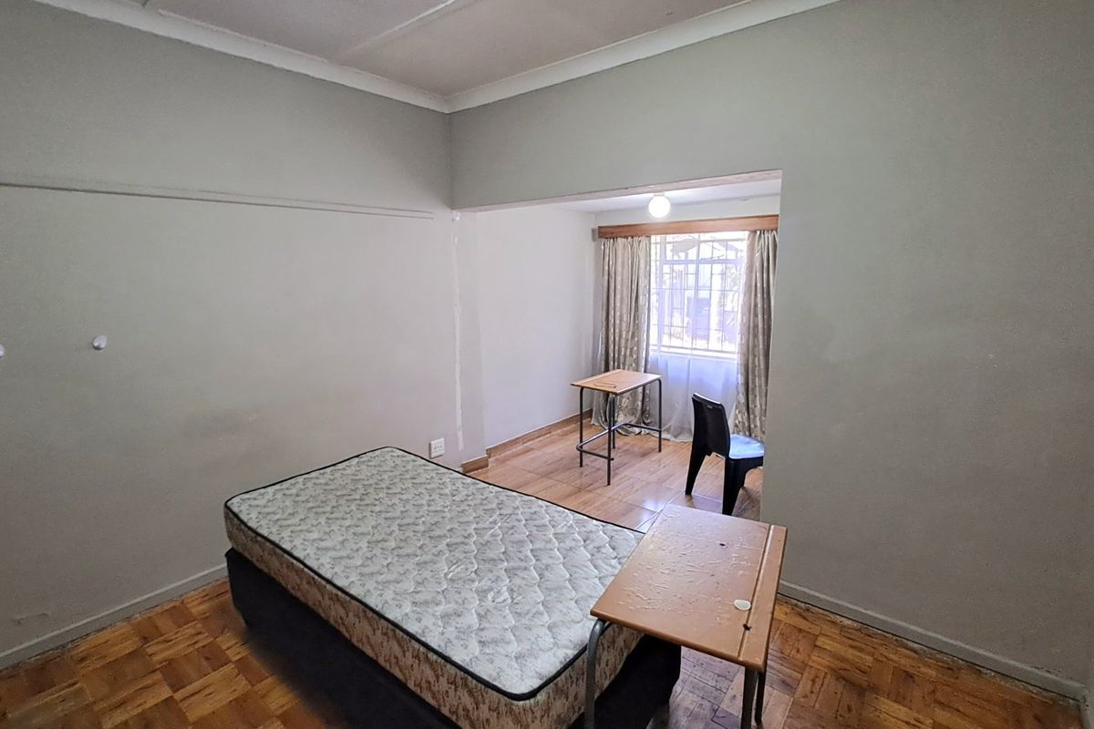 A bedroom featuring parquet flooring and a recessed window area, offering a blank canvas for renovation or staging.