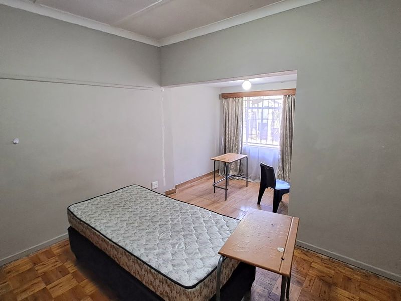 A bedroom featuring parquet flooring and a recessed window area, offering a blank canvas for renovation or staging.