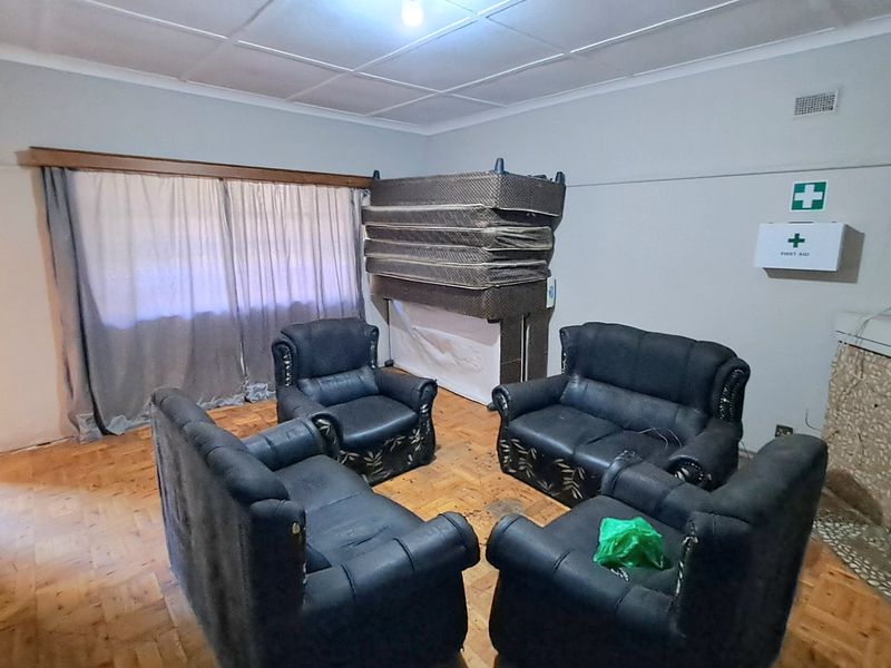 A living room featuring parquet flooring and a stone-clad fireplace, offering a dated interior space with potential for renovation and modernization.