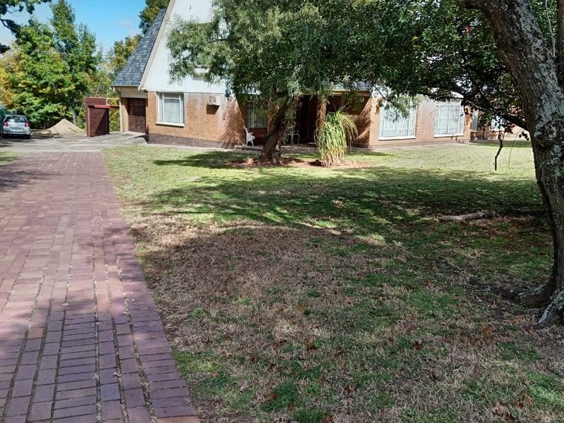 Front view of a residential house featuring a brick facade, pitched roof, and a paved driveway leading to the property entrance.