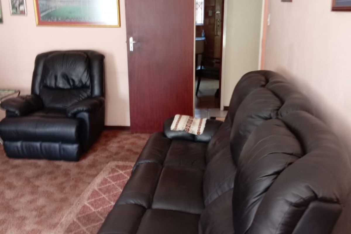 A living room featuring carpeted flooring and a standard internal door with a transom window above, leading to an adjacent space.