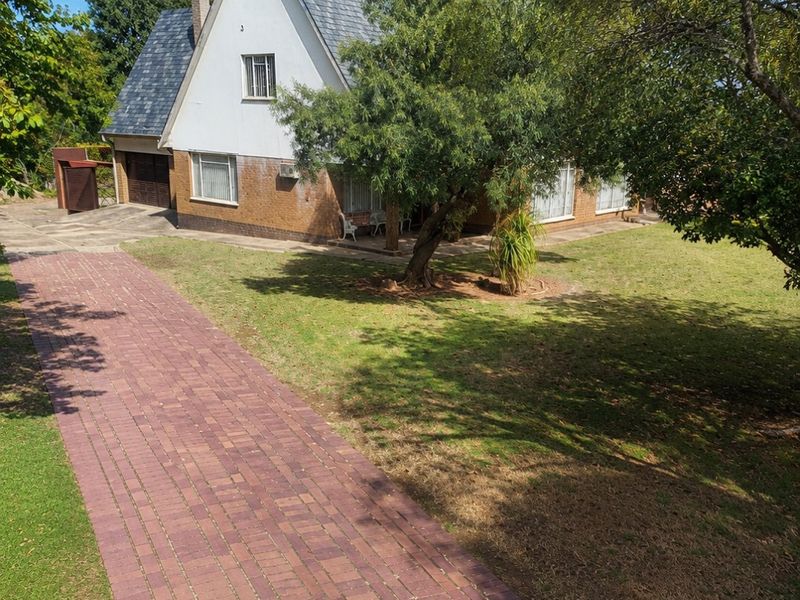 A detached house featuring a brick driveway, slate roof, and established garden, showcasing a traditional architectural style with a front-facing garage.