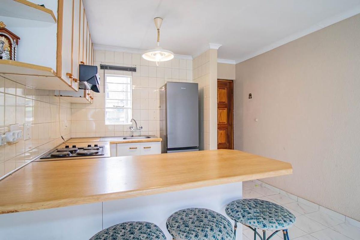 Functional kitchen featuring built-in cabinetry, a gas hob with extractor, tiled backsplash, and a breakfast bar counter, offering a practical layout for daily use.