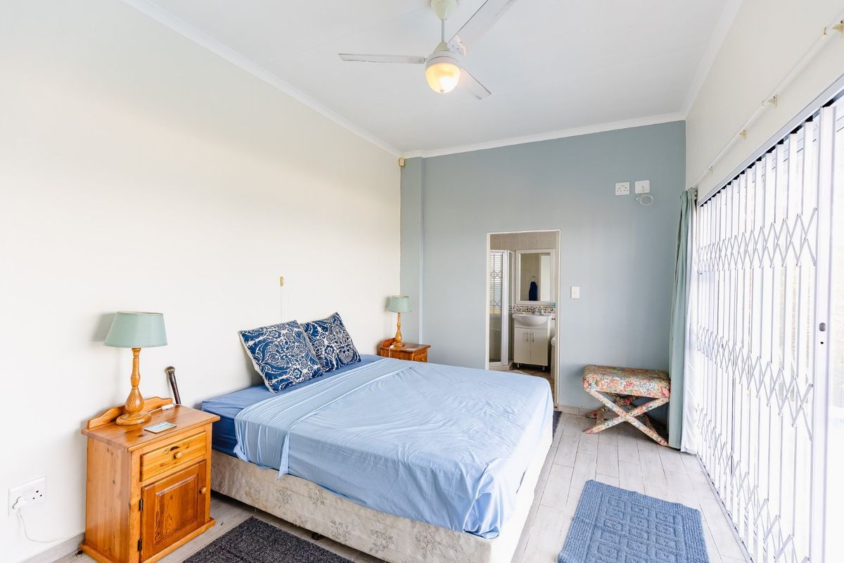 A bedroom featuring tiled flooring, a ceiling fan, and direct access to an en-suite bathroom, with a security gate leading to the exterior.