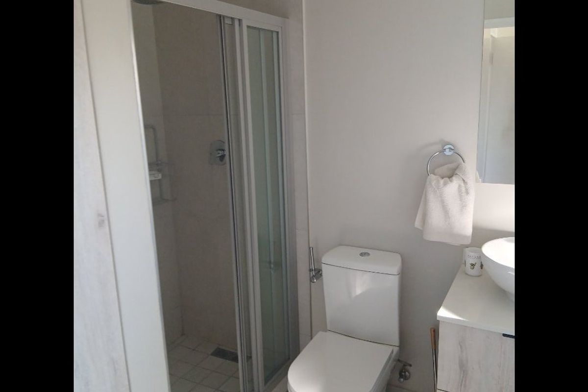 A functional bathroom featuring a glass-enclosed shower, a modern toilet, and a vanity cabinet with a basin.