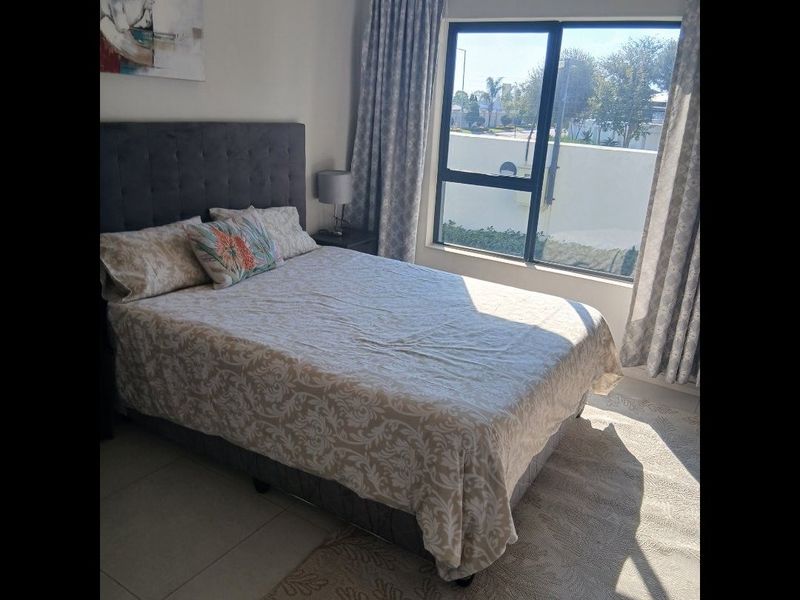 A well-lit bedroom featuring tiled flooring and a large window that allows for ample natural light.
