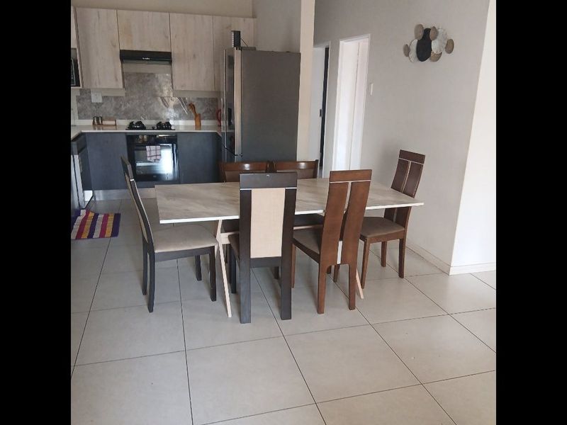 Open plan kitchen and dining area featuring modern cabinetry, built-in oven, hob, extractor fan, and neutral tiled flooring throughout.